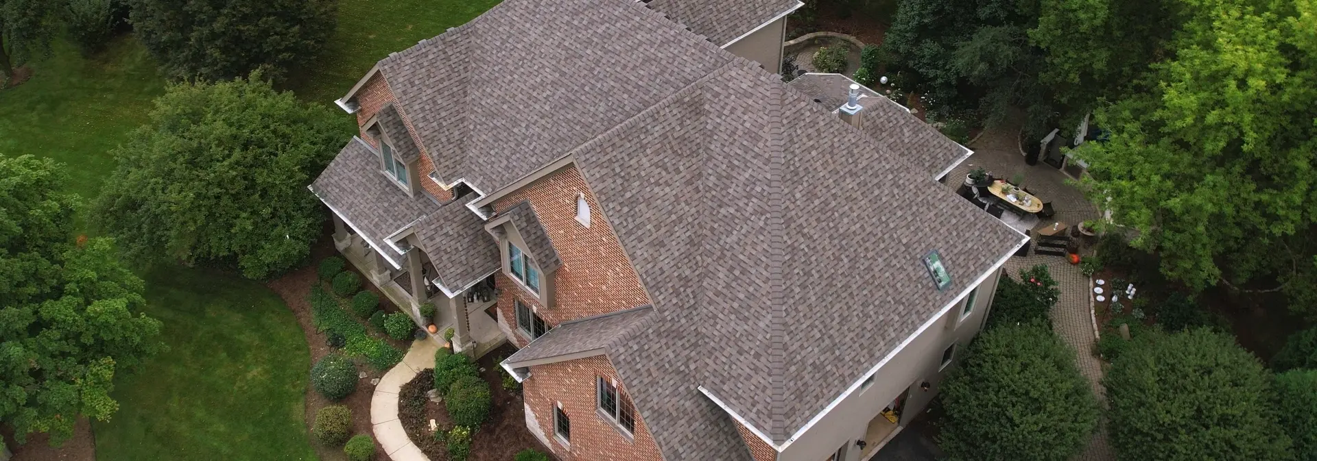 Aerial view of a large brick home with new gutters courtesy of 3JM Exteriors